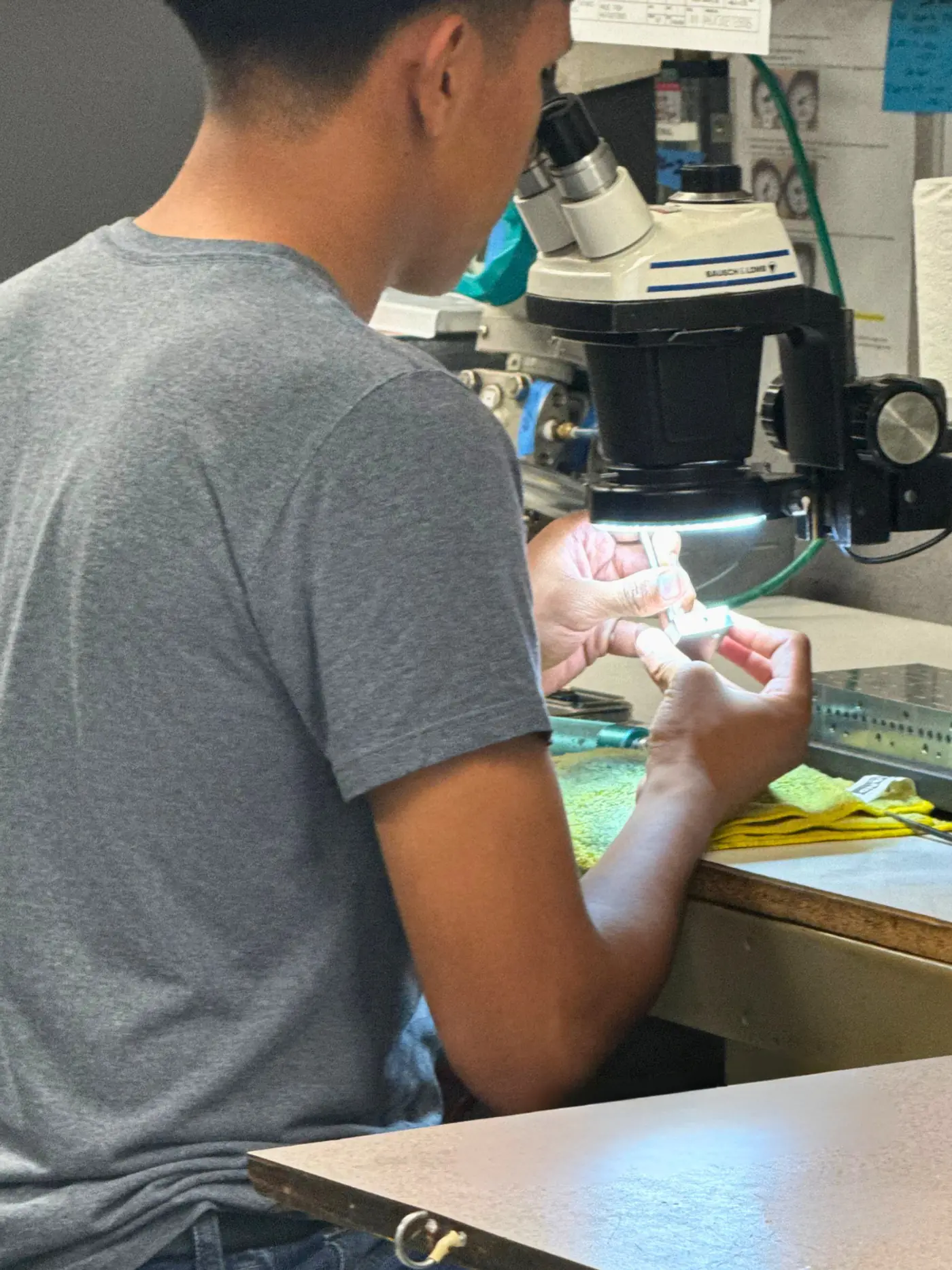 Machinist inspecting a finished part under a stereo microscope at the inspection bench