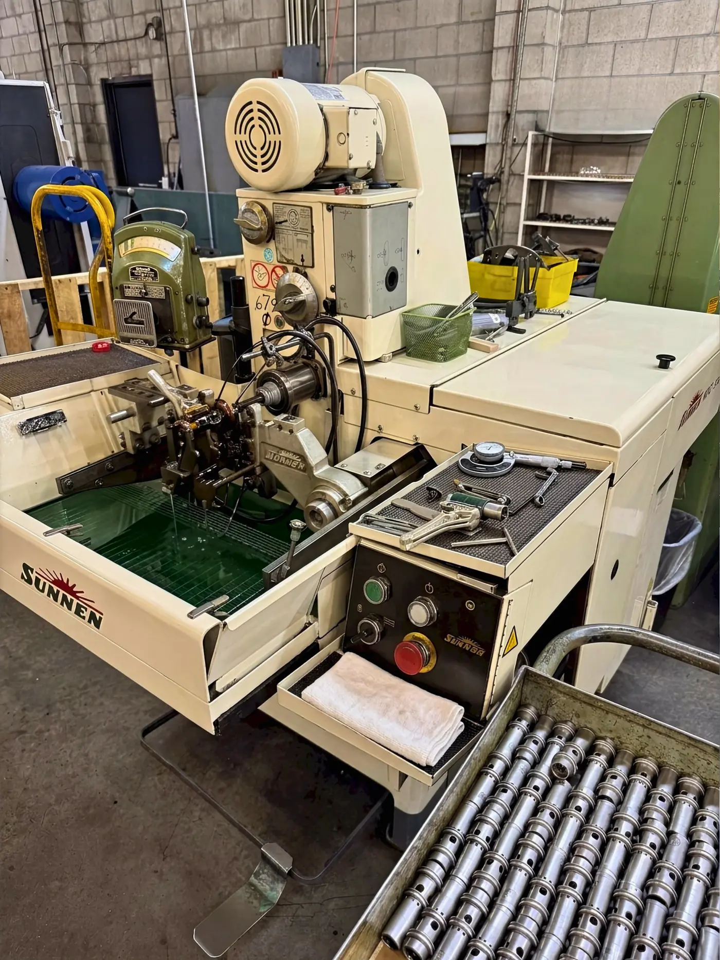 Sunnen honing machine set up mid-job, with a dial bore gauge and micrometers on the tool tray