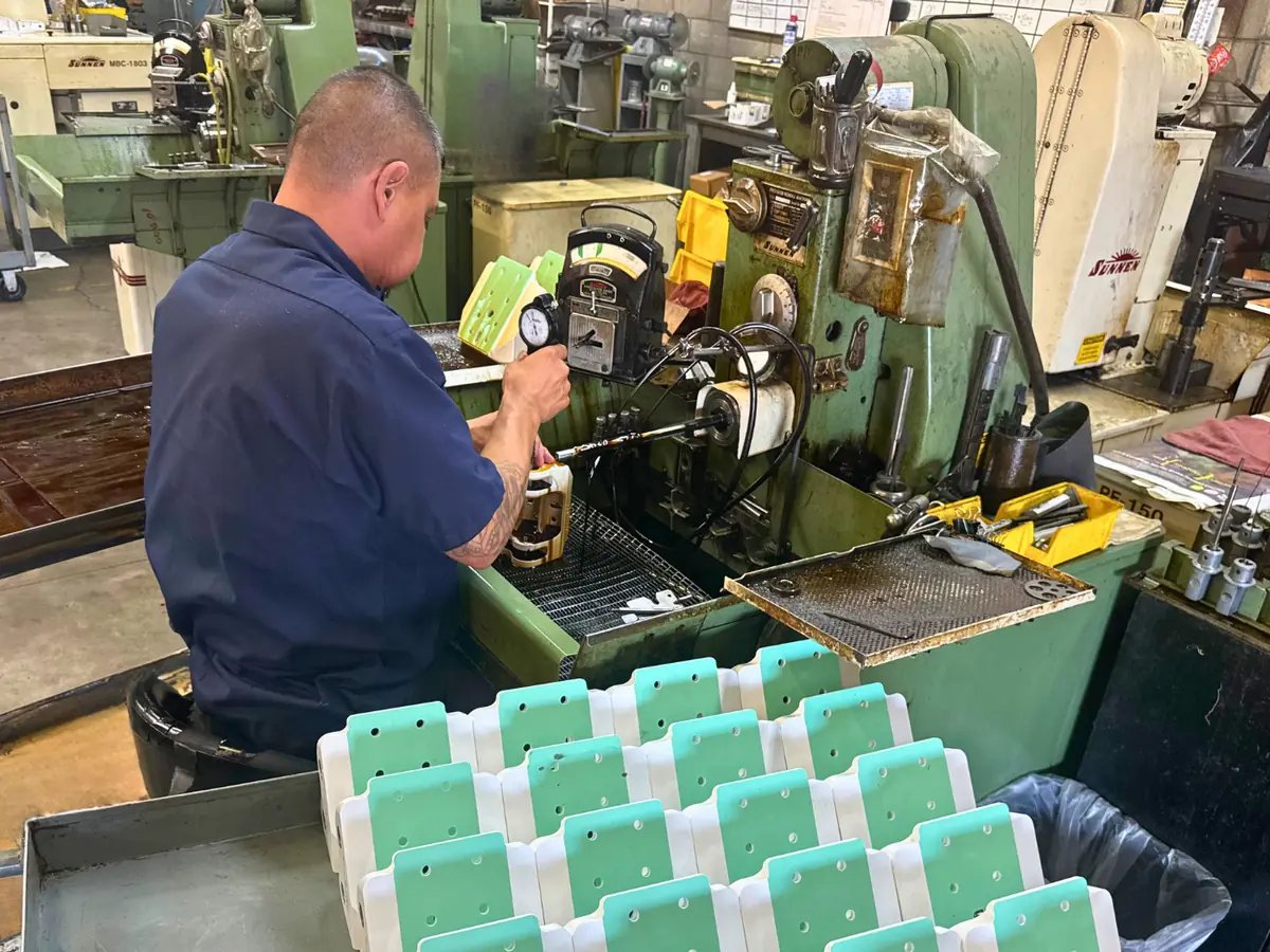 Machinist honing a bore on a Sunnen honing machine, the rest of the run staged in front of him