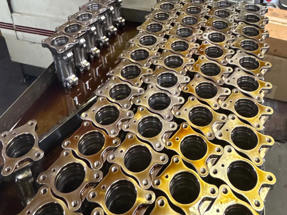 Rows of flanged housings on the honing machine table, bores finished and wet with honing oil