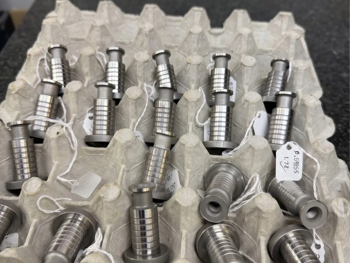 Precision ground stepped plungers in a tray, each tagged with its measured diameter